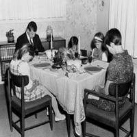 Zreli par sa svojom troje djece koji se mole na trpezarijskom stolu na Dan zahvalnosti Print